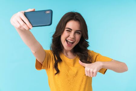 Image of positive happy optimistic young pretty woman posing isolated over blue wall background take...