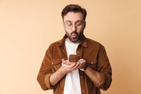Portrait of a cheerful young arttractive bearded man wearing casual clothes standing isolated over...