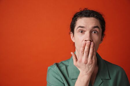 Image of young handsome man expressing shock on camera isolated over orange background