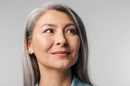 Image of adult mature woman with long white hair wearing shirt looking aside at empty space isolated...