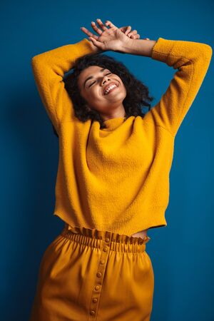 Image of a pretty happy positive optimistic young african woman posing isolated over blue wall background.の写真素材