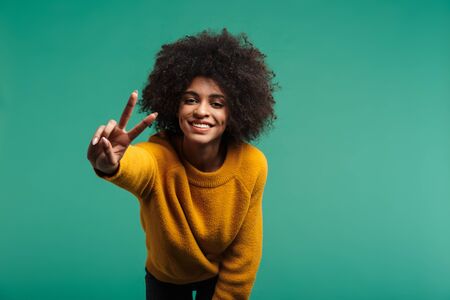 Image of a positive optimistic african curly woman posing isolated over dark blue wall background...