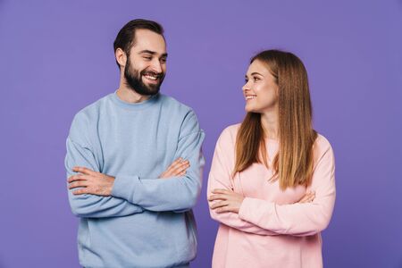 Photo of a positive happy young loving couple isolated over purple background.