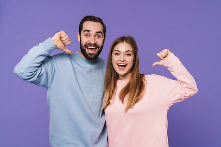 Picture of a happy positive young loving couple isolated over purple background pointing to themselves.の写真素材