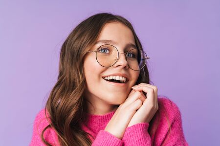 Image of young beautiful woman wearing eyeglasses smiling and looking upward isolated over violet backgroundの写真素材