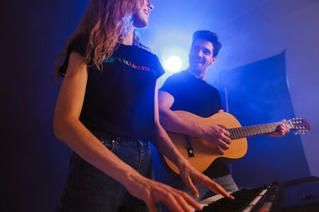 Image of young loving couple musicians group duet on scene in night club over dark background with...