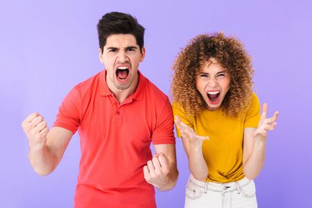 Portrait of happy caucasian people man and woman in basic clothing screaming and rejoicing together isolated over violet backgroundの写真素材