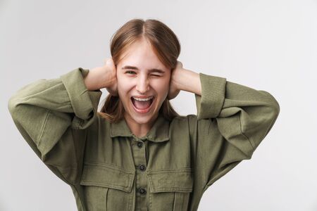 Photo of annoyed young woman screaming and grabbing her head isolated over white backgroundの写真素材
