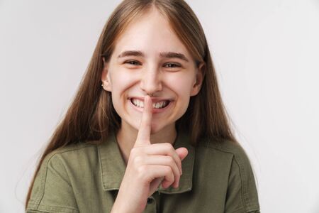 Photo of happy caucasian woman making silence gesture and smiling isolated over white backgroundの写真素材