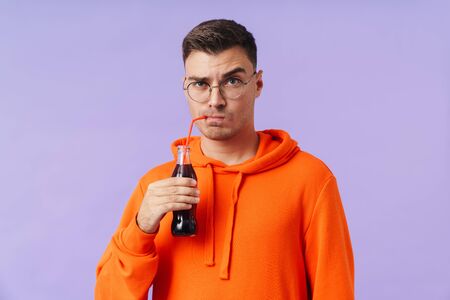 A confused serious man holding bottle with soda.