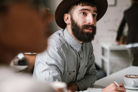 Multiethnic young female and male colleagues discussing business ideas at table while working in officeの写真素材