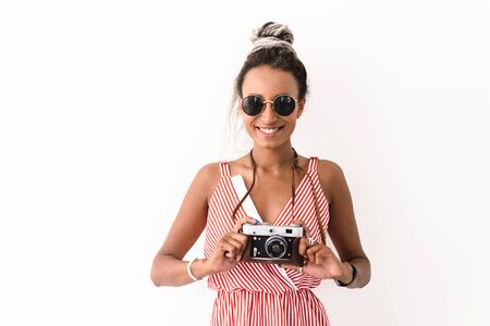 Photo of a happy optimistic young cute african woman photographer tourist with dreads posing...