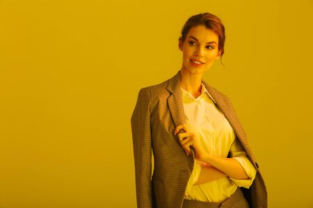 Image of joyful pretty woman in formal suit smiling and looking aside isolated over yellow backgroundの写真素材