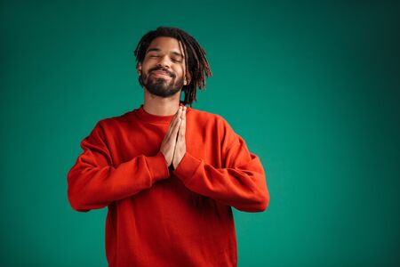 Portrait of a smiling young african man wearing pullover standing isolated over green background,...