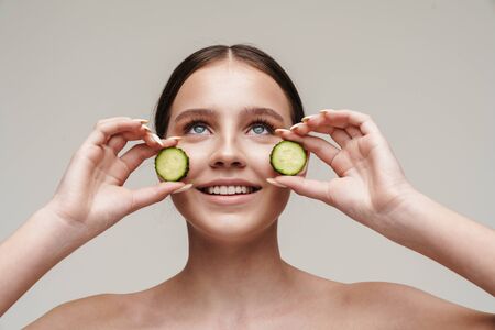 Image of beautiful joyful shirtless woman posing with cucumber and smiling isolated over grey backgroundの写真素材