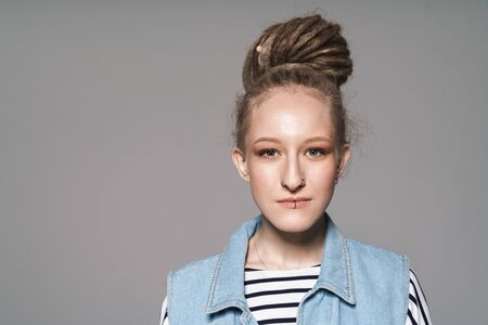Image of young extraordinary girl with face piercing and dreadlocks looking at camera isolated over gray backgroundの写真素材