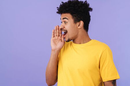 Photo of excited african american man looking aside and screaming isolated over purple backgroundの写真素材