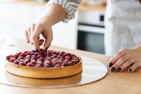 Cropped image of caucasian woman cooking pie with raspberries in modern kitchenの写真素材