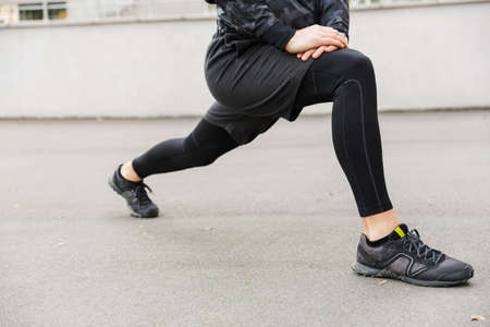 Cropped image of a young fit sportsman working at the stadium racetrack, doing stretching exercises
