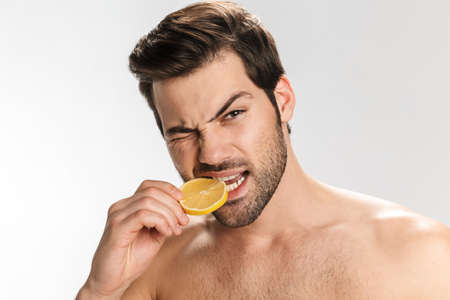 Photo of happy half-naked man with cosmetic clay mask on his face and towel smiling at camera isolated over white backgroundの写真素材