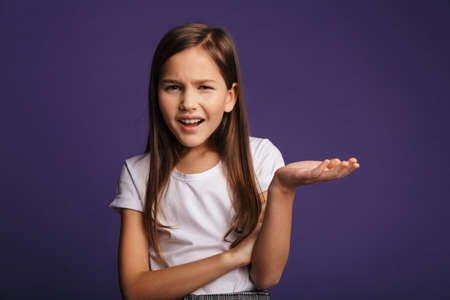 Photo of displeased beautiful girl holding copyspace and looking at camera isolated over purple...