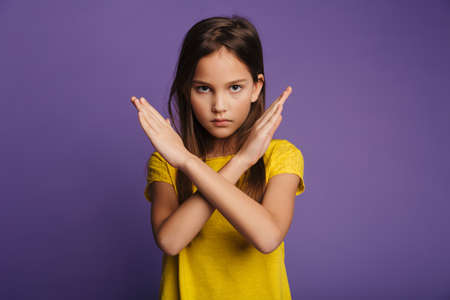 Photo of displeased pretty girl showing stop gesture with hands on camera isolated over purple...