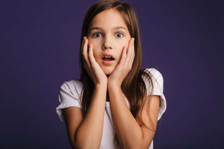 Photo of astonished pretty girl expressing shock on camera isolated over purple background