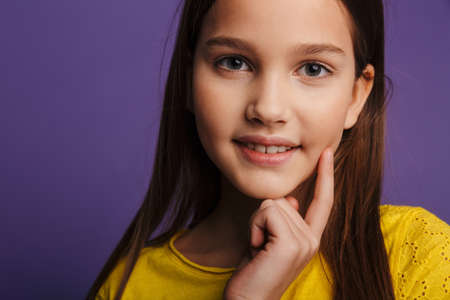 Photo of happy beautiful girl smiling and looking at camera isolated over purple background