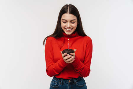 Photo of happy caucasian woman smiling and holding cake with candle isolated over white backgroundの写真素材