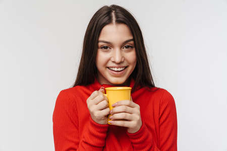 Photo of cheerful brunette woman laughing and holding cup isolated over white backgroundの写真素材