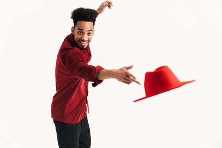 Image of a handsome african positive young man posing isolated over white wall background throwing a hatの写真素材