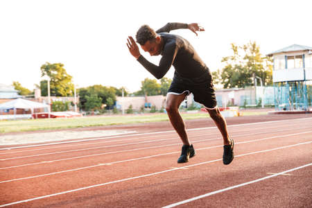 Image of active african american man running on sports stadium outdoorsの写真素材