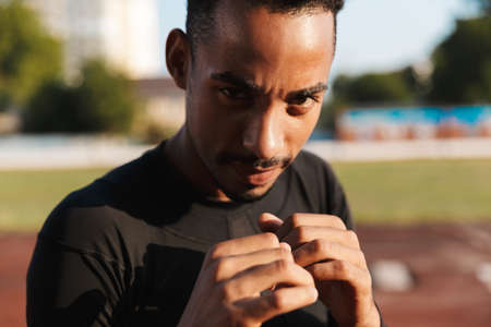 Image of athletic african american man clenching fists and boxing on sports ground outdoorsの写真素材