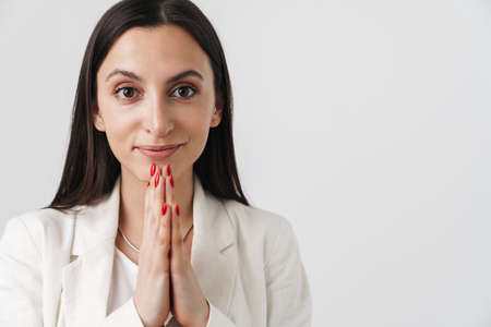 Photo of young smiling businesswoman posing with palms together isolated over white background
