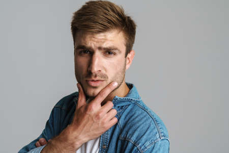Portrait of confident redhead man posing and looking at camera isolated over grey backgroundの写真素材