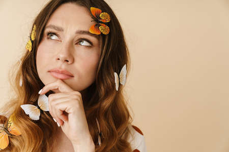 Photo of beautiful perplexed woman with fake butterflies posing and looking aside isolated over...