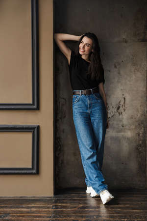 Photo of beautiful young brunette woman smiling and looking aside isolated over concrete background