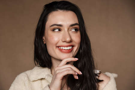 Photo closeup of funny cute woman laughing and looking aside isolated over beige background