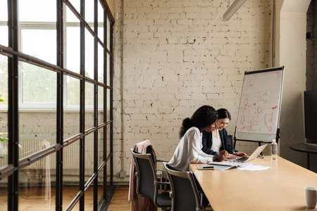 Confident smiling smart women entrepreneurs working on a new startup project while sitting at the...