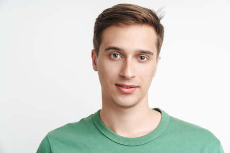 Image of young caucasian man in basic t-shirt looking at camera isolated over white background
