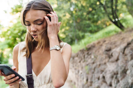 Image of young caucasian brunette woman wearing braces smiling while walking in parkの写真素材