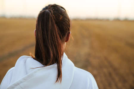 Image from back of adult beautiful sportswoman running while working out at golden fieldの写真素材