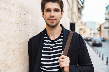 Photo of a young handsome young business man walking by street outdoors