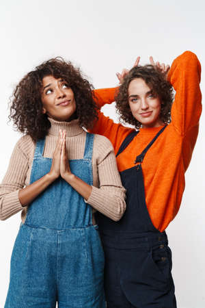 Image of a beautiful happy cheery optimistic two multiracial girls friends in denim jumpsuits...
