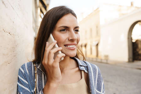 Happy woman using a smart phone on the street, talking on mobile phone