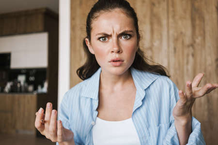 Image of a young angry displeased girl indoors at home holding pencil while talking to you