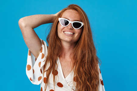 Portrait of a beautiful cheerful young woman with long red hair wearing summer clothes and...