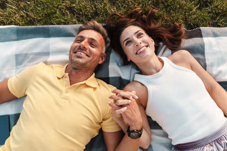Image of a beautiful happy adult loving couple lies outdoors in a beautiful green nature park.の写真素材