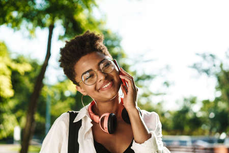 Young cheerful woman chit-chatting on a phone outdoors, close up