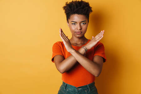 Image of serious african american woman showing on camera isolated yellow backgroundの写真素材